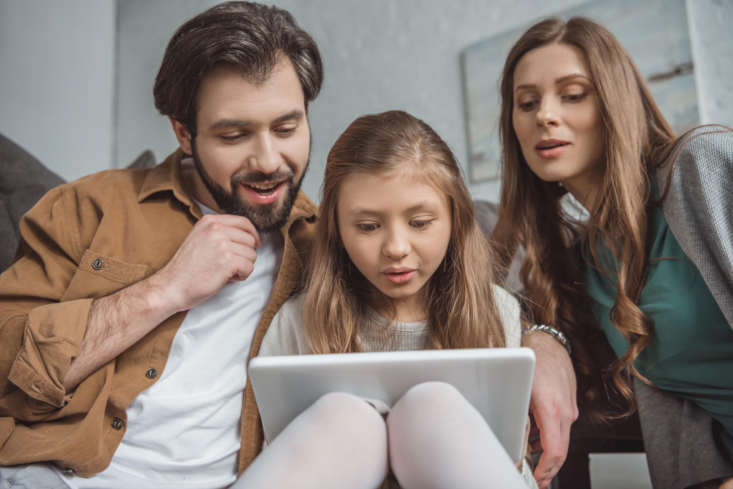 To forældre og et barn foran en tablet